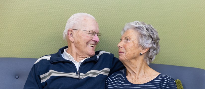 Bewoner en partner kijken elkaar liefdevol aan in de Judith Leysterhof.