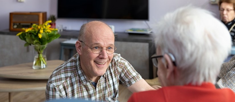 Rivas Medewerker Zit Voor Bewoonster Op Zijn Knieen En Lacht Naar Mevrouw